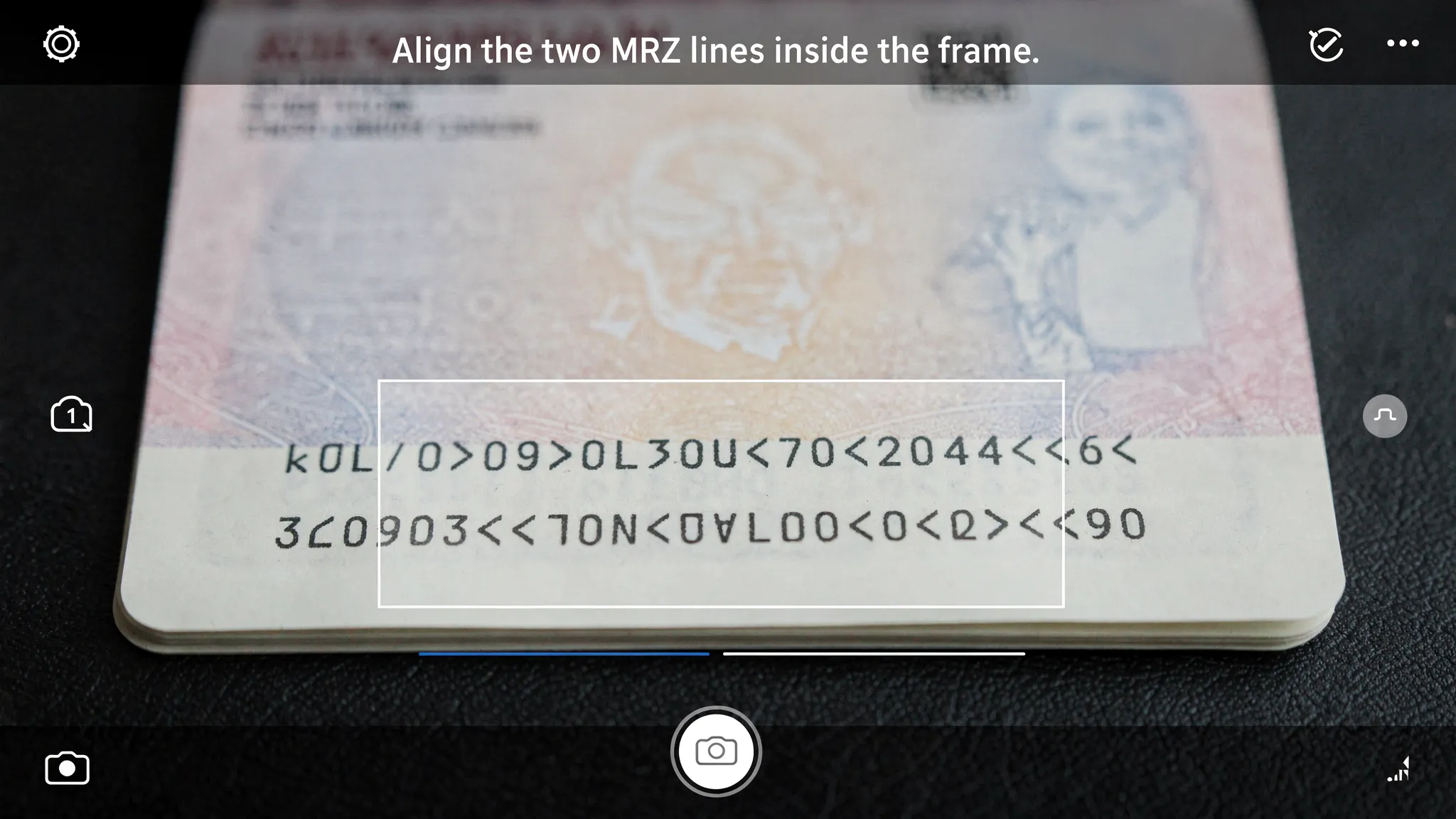 A smartphone camera view framing the bottom of a passport page with a highlighted MRZ box. The scene shows clear, glare-free lighting, the passport lying flat on a dark table, and on-screen guidance text like “Align the two MRZ lines inside the frame.”